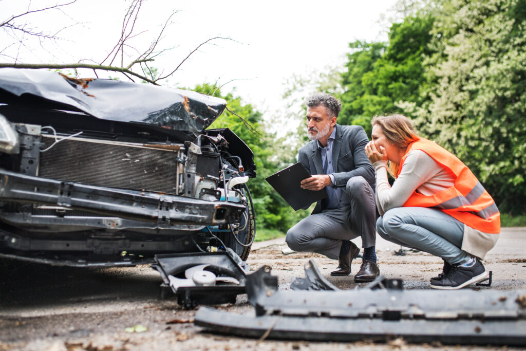 An insurance fraud private investigator agent and a woman looking at the car on the road after an accident. 